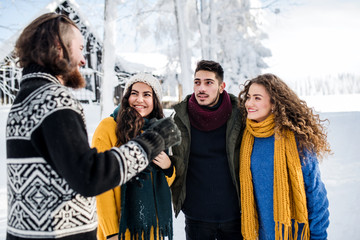 A group of young friends on a walk outdoors in snow in winter.