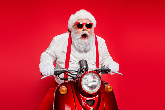 Portrait of nice attractive bearded crazy cheerful cheery funny funky Santa riding motor bike delivering shop orders hurry up isolated over bright vivid shine vibrant red color background