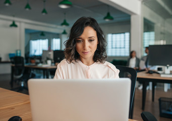 Focused young businesswoman working on her laptop in an office