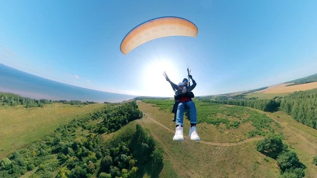 Front view of two people flying on the paraglider. Man Paragliding, beautiful nature background.