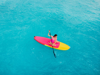 Attractive woman on stand up paddle board on a quiet blue ocean. Sup surfing in sea