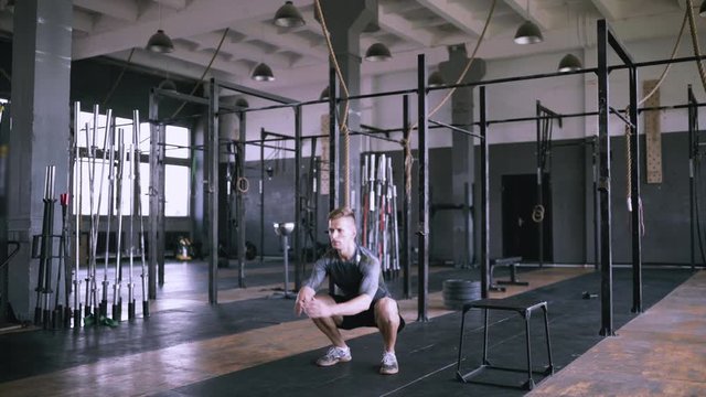 Powerlifting effective jumps. Male fitness instructor showing squat exercise at loft plase. Jumping squats at gym. Effective exercises for a great fit. lunch short workout.