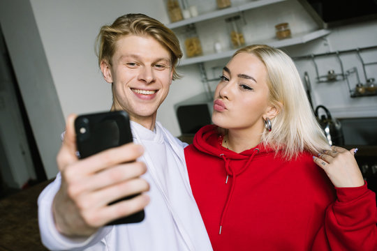 Adorable stylish blonde couple posing for selfie with cell phone. Having fun with online social media communication