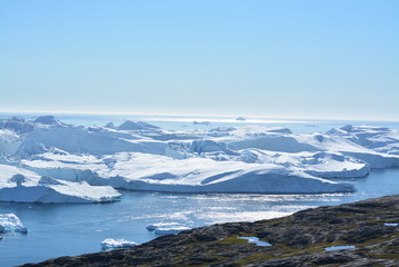 Fototapeta na wymiar great views over ice fjord in Ilulissat Greenland - beautiful icebergs in the Disko Bay / Baffin Bay - blue sky, ice sea