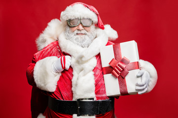 Portrait of calm dreamy magic eve elderly santa claus carry sack bag deliver giftboxes in snowy weather wear white gloves costume hat protection isolated over red background