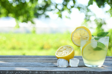 Glasses of lemon juice on a wooden table, summer set, outdoor greed blured background,boke.Water...