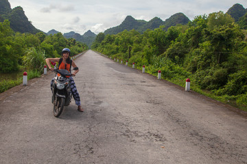 girl biker riding a scooter in the mountains of Vietnam, Woman in blue helmet riding scooter motorbike, Female traveler riding a motorcycle scooter in Vietnam