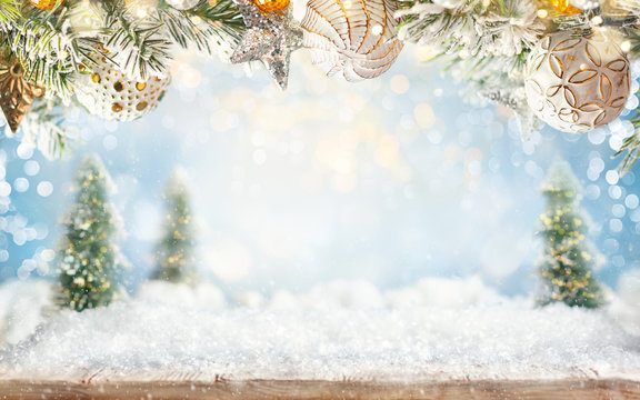 Beautiful winter background with wooden old desk, fir trees and blurred blue sky. Winter, New Year and Christmas concept with snowy background.