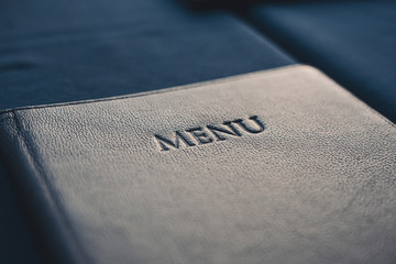 Dark blue menu book on table in restaurant, selective focus - obrazy, fototapety, plakaty