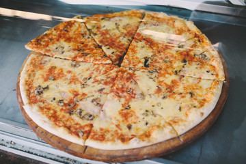 Hot pizza displayed inside display case in street restaurant