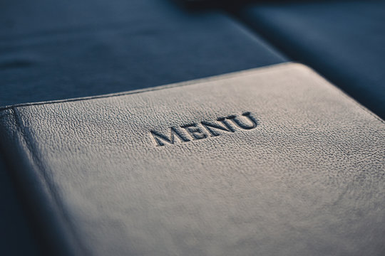 Dark blue menu book on table in restaurant, selective focus
