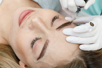 Permanent makeup, tattooing of eyebrows. Cosmetologist applying make up