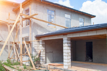 facade of cottage under construction covered with plaster with new windows inserted