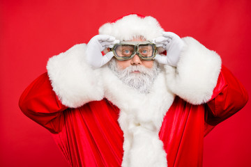 Close up photo of focused funky cool santa claus fix his goggles before rocket flight wear white gloves cap isolated over red color background
