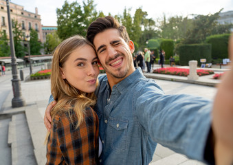 Obraz premium Stylish tourist couple taking pictures selfie on smart phone on romantic trip around Europe