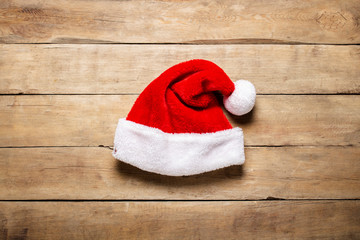 Obraz na płótnie Canvas Santa Claus hat on a wooden background. The concept of Christmas, winter holidays, New Year, greeting card, retro style. Flat lay, top view
