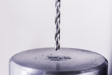 metal drill bit make holes in steel billet on industrial drilling machine. Metal work industry....
