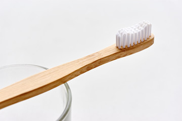 Closeup of a wooden toothbrush. Simple bamboo biodegradable eco toothbrush on a drinking glass...