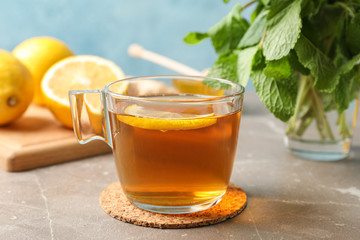 Cup of tea with lemon and mint on grey background, close up