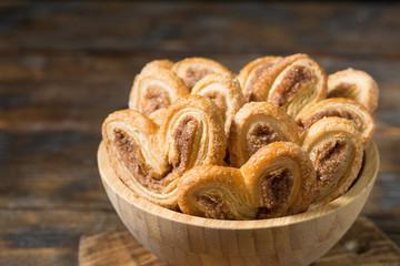 Puff pastry with sugar and cinnamon in a wooden bowl. Rustic style. Space for text