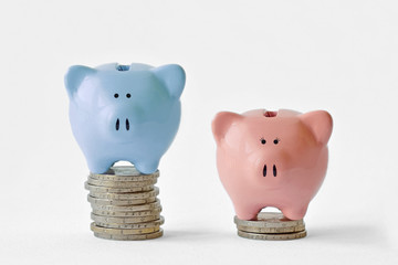 Blue and pink piggy bank on stack of coins - Gender pay gap concept