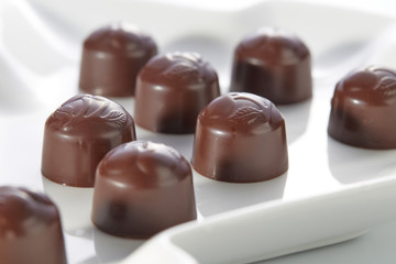 Chocolate candies with cherry filling without wrappers laid out on a white plate close-up. Dolce vita.
