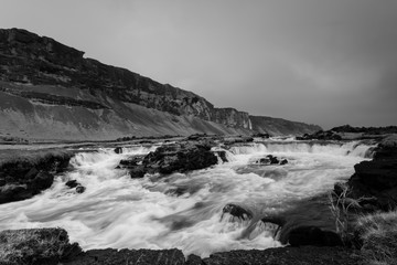 Black and white photo of river flowing between the mountains.South Iceland