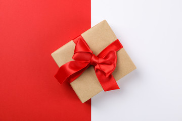 Beautiful gift box with red bow on two tone background, space for text