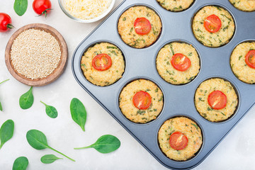 Savory muffins with quinoa, cheese and spinach topped with tomato, in  muffin tin, horizontal, top view
