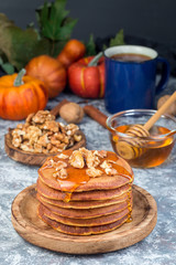 Delicious homemade pumpkin pancakes served with walnuts and honey, autumn decoration, vertical