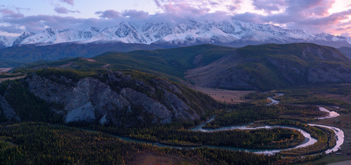 Beautiful sunset landscape panorama of Kurai steppe with chuya river, incredible mountain ice peaks of Siberia and sunset sky on background. Natural scenery of autumn mountain forest. Altai, Siberia.