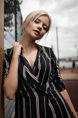 Obraz premium Piękna młoda elegancka kobieta uwodzicielska pozowanie na placu zabaw w pobliżu bramy. Seksowny modelka moda seksowna dziewczyna w klasycznej sukience i obcasach. Stylowy portret uroda