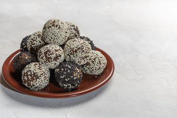 Homemade energy balls on a brown ceramic plate on a white background
