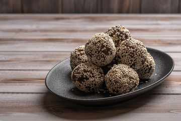 Homemade energy balls on a black plate on a wooden background