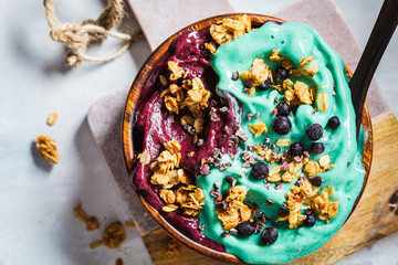 Healthy vegan breakfast. Blue spirulina and berries smoothie bowl, gray background.