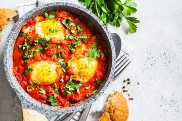 Traditional shakshuka in  pan. Fried eggs in tomato sauce with herbs, top view.