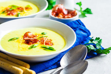 Cheese soup with bacon and green onions in white plate, white background.