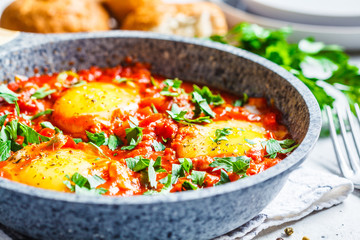 Traditional shakshuka in  pan. Fried eggs in tomato sauce with herbs.