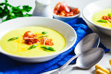 Cheese soup with bacon and green onions in white plate, white background.