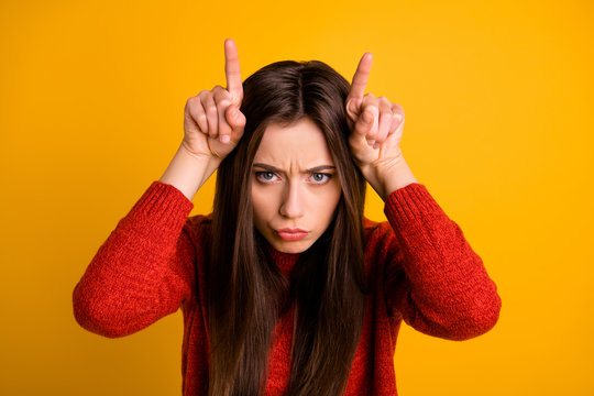 Photo of frowning sullen disappointed disobedient girl showing you bull horns isolated over vivid color background