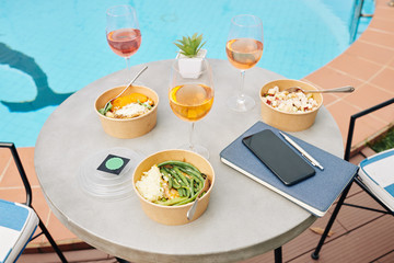 Dinner served for three people. Glasses of wine and cardboard bowls with tasty salads
