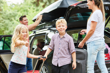 Siblings help children to carry suitcases