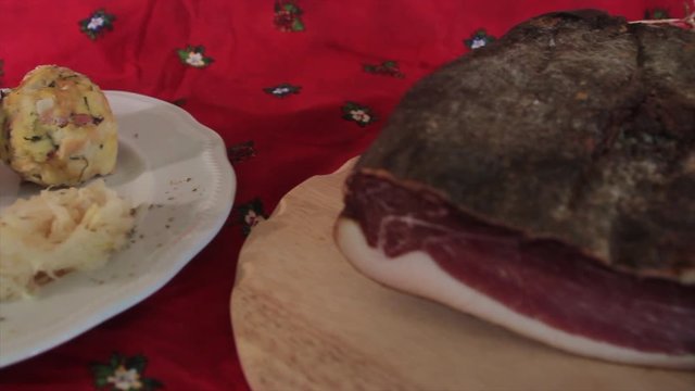 fly over two knodels on the plate with sauerkraut and speck on the background and mug of beer and Christmas tablecloth
