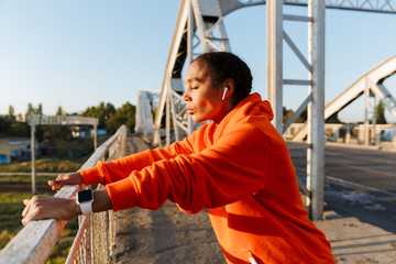 Obraz premium Photo of african american woman using earpods while leaning on railing