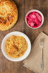 Pilaf in a plate, Asian bread, salted cabbage on the table