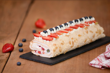 Meringue roll cake decorated with blueberries and strawberries.