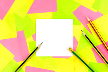 The white paper note and four pencils put on colorful sticky note background..