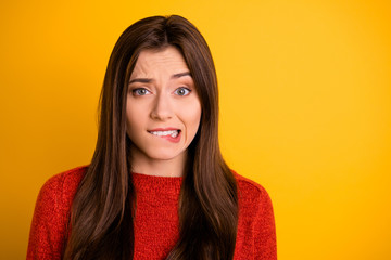 Portrait of disappointed scared girl bite her lips have trouble worry feel panic expression emotion wear red sweater isolated over yellow color background