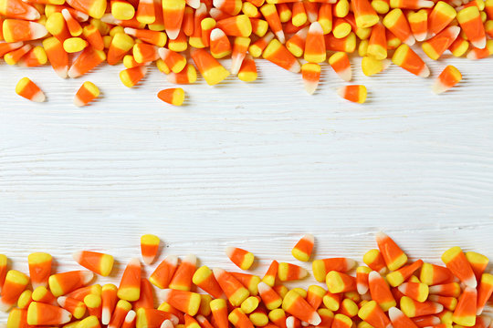 Bunch of candy corn sweets as sybol of Halloween hoiday on textured background with a lot of copy space for text. Flat lay composition for all hallows eve. Top view shot.