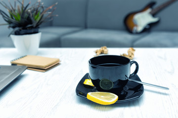 Home office and work in apartment concept. A cup of tea with a lemon on the table at the computer...